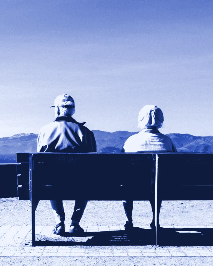 Pareja de adultos mayores sentados en una banca, vista de espaldas