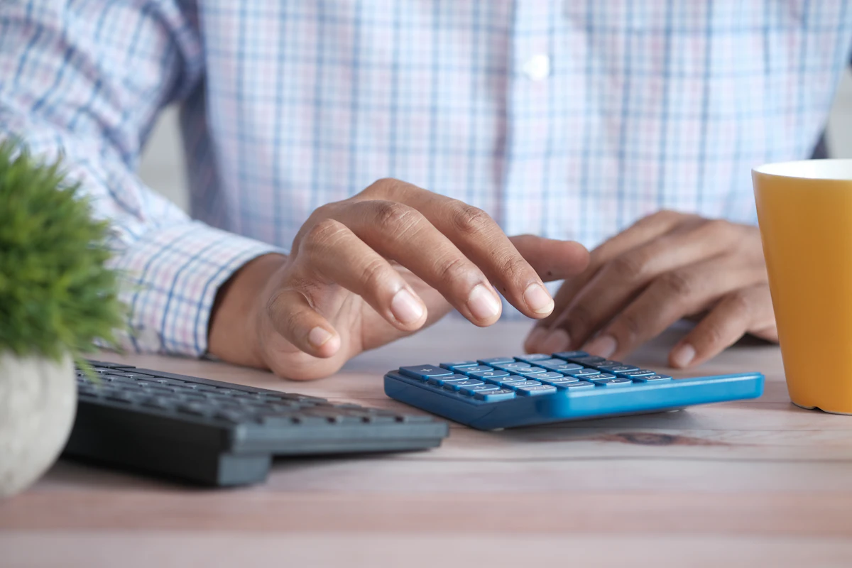 Manos usando una calculadora sobre un escritorio